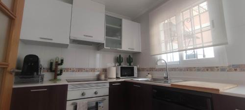 Una cocina con gabinetes blancos, un fregadero y un microondas. en Villa Terreros, en San Juan de los Terreros