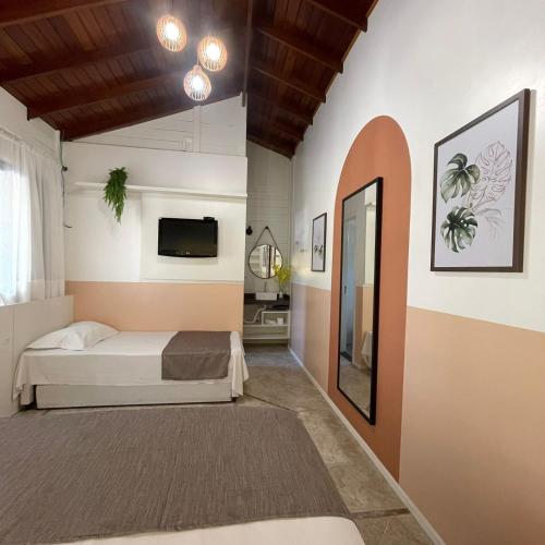 a bedroom with a bed and a tv on the wall at Pousada Casa Mariscal in Bombinhas