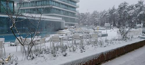 a table and chairs covered in snow in front of a building at Apartament z widokiem na morze Międzyzdroje in Międzyzdroje