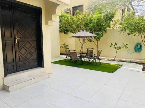 a patio with a table and chairs and an umbrella at FANATEER SUDAYER VILLA in Al Fanātīr