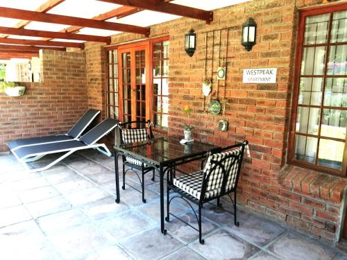 a patio with a table and chairs on a brick wall at Gästehaus HelderbergView in Somerset West