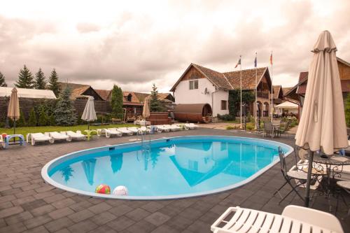 una gran piscina con sillas y sombrilla en Pensiunea Sachsenhof, en BÄƒgaciu