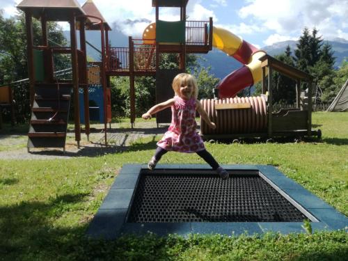 a little girl standing on a grate in a playground at nawu apartments & Restaurant in Hermagor