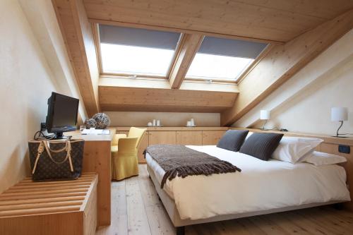 a bedroom with a bed and a tv and windows at Palace Hotel Wellness & Beauty in Bormio