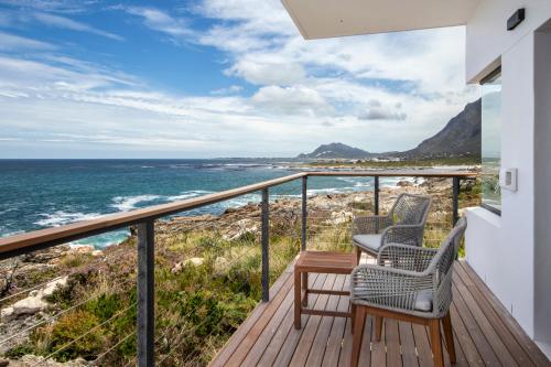 two chairs on a balcony overlooking the ocean at OnTheRocksBB Solar Powered Guesthouse and Ocean Lodge in Bettyʼs Bay