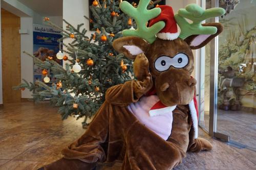 a costume of a reindeer in front of a christmas tree at nawu apartments & Restaurant in Hermagor