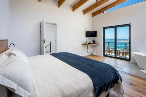 a bedroom with a bed and a bathroom with a tub at OnTheRocksBB Solar Powered Guesthouse and Ocean Lodge in Bettyʼs Bay