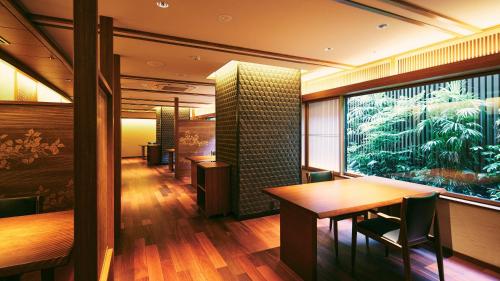 a restaurant with a table and chairs and a large window at Sora Niwa Terrace Kyoto Bettei in Kyoto