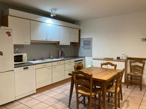 une cuisine avec une table et des placards blancs dans l'établissement Gite La Janiat, à Montigny-sur-lʼAin
