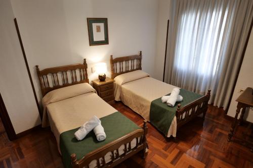 Dos camas en una habitación de hotel con toallas. en Hostal Cristina en Estella