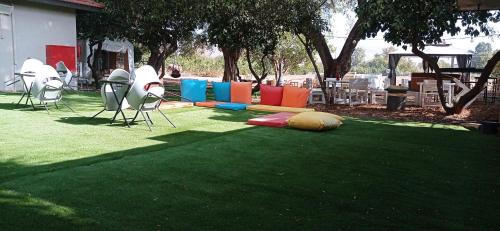 a lawn with chairs andools on the grass at אחוזת המייסדים in Bet Hillel