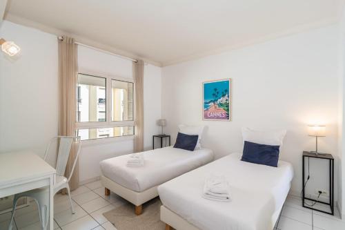 2 łóżka w białym pokoju z biurkiem i oknem w obiekcie Général Ferrié 3 pcs AR Croisette Martinez by Olam Properties w Cannes