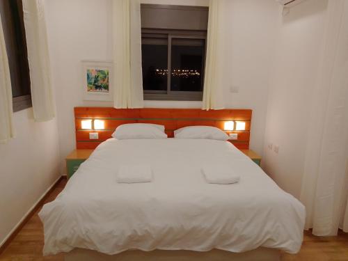 a bedroom with a large white bed with a window at Beautiful beach apartment in Ashdod