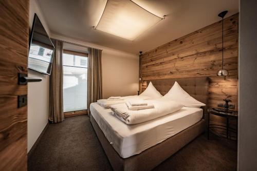 1 dormitorio con 1 cama grande y pared de madera en Cozy Loft in the Alps of Zillertal, en Schwendau