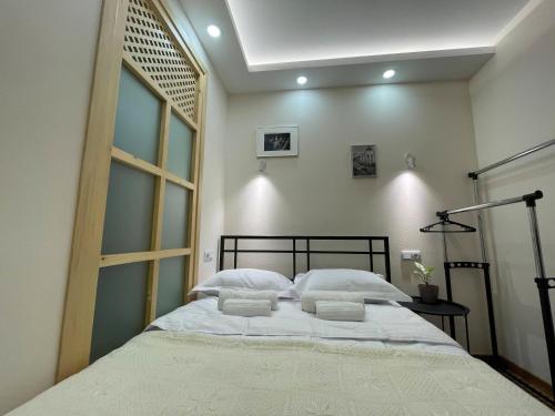 una camera da letto con un grande letto con lenzuola e cuscini bianchi di LT-Home a Tbilisi City