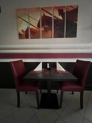 a table and two chairs in a restaurant with paintings at Hotel-Gasthof "Alter Ritter" in Rothenburg ob der Tauber