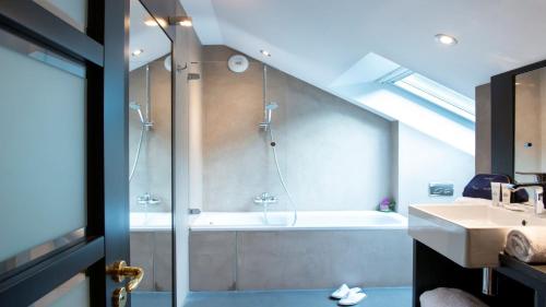 a bathroom with a shower and a tub and a sink at Les Trésoms Lake and Spa Resort in Annecy