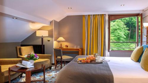 a hotel room with a bed and a living room at Les Trésoms Lake and Spa Resort in Annecy