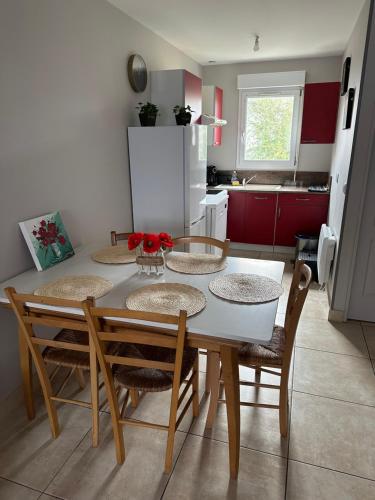 a dining room table with four chairs and a kitchen at Magnolia58 in Pontault-Combault