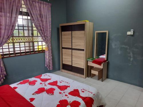 a bedroom with a bed with red flowers on it at Jerai Geopark Cottage 3 bedrooms -Pulau Bunting in Yan