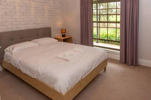 a bedroom with a large bed with a window at Furche Barossa Vineyard Family Stay 