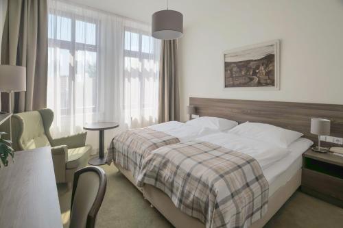 a hotel room with a bed and a chair and window at Hotel Zlatá Hvězda in Litomyšl