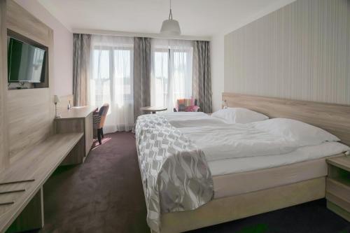 a bedroom with a bed and a desk and a television at Hotel Zlatá Hvězda in Litomyšl