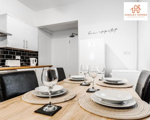 a wooden table with wine glasses and plates on it at Stylish Home 8 Guests - Liverpool - Free Wifi & Parking By Hinkley Homes Short Lets & Serviced Accommodation in Liverpool