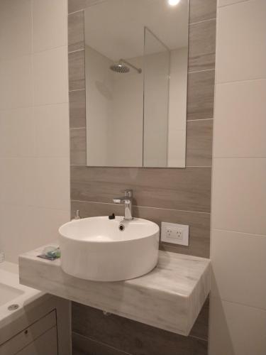 y baño con lavabo blanco y espejo. en Zona Güemes departamento nuevo en Mar del Plata