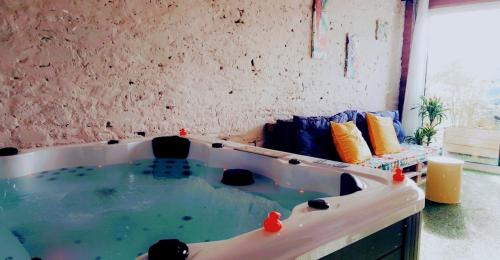 uma banheira de hidromassagem num quarto com um sofá em Gîte Evanez Mont-saint-Michel jacuzzi intérieur privatif illimité em Pontorson