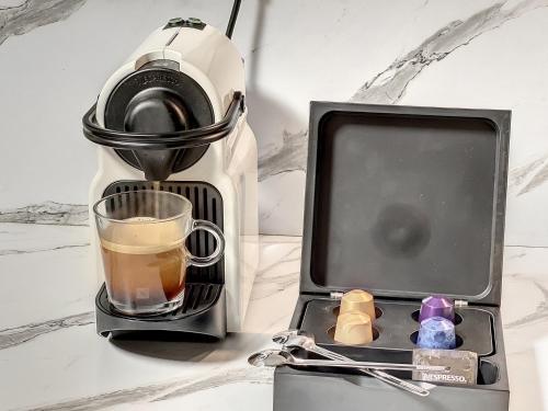 een koffiezetapparaat met een kopje en een glas koffie bij Cocon Blanc câlin - Jacuzzi privatif - Love Room à Saint Etienne in Saint-Étienne