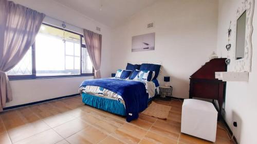 um quarto com uma cama azul e uma janela em Alpero Umtentweni em Port Shepstone