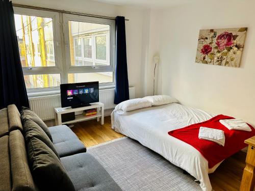 a bedroom with a bed and a couch and a tv at X Leysdown Apartment Camden in London