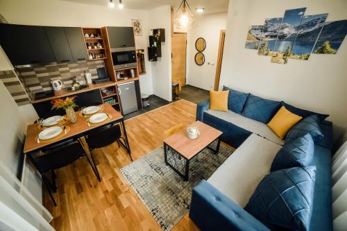 Unikat Zlatibor في زلاتيبور: غرفة معيشة مع أريكة زرقاء وطاولة