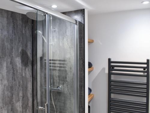 La salle de bains est pourvue d'une douche avec une porte en verre. dans l'établissement Newlands Farm Cottage Halifax, à Luddenden Foot