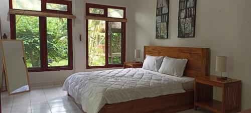 1 dormitorio con 1 cama y 2 ventanas en Taman Lituhayu Cottages, en Ubud
