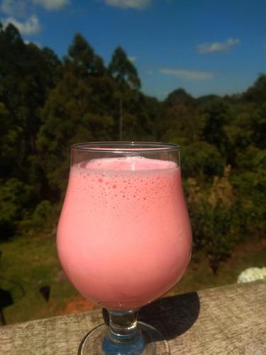 Pousada Vale do Horizonte في مونتي فيردي: مشروب وردي في كوب موضوع على طاولة