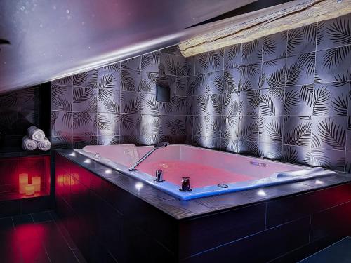 ein Badezimmer mit einer Badewanne und roten Lichtern in der Unterkunft Suite Privative Rouge baiser - Spa & Jacuzzi - Love Room à Saint Etienne in Saint-Étienne