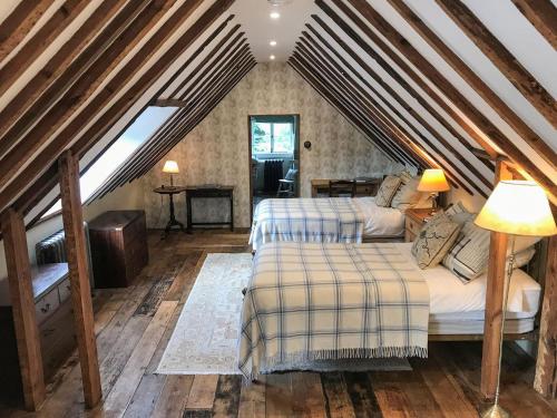 a attic bedroom with two beds and a staircase at Old Rectory Loft in Fernhurst