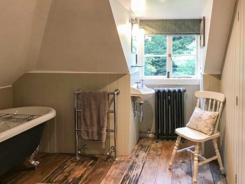 a bathroom with a tub and a sink and a chair at Old Rectory Loft in Fernhurst