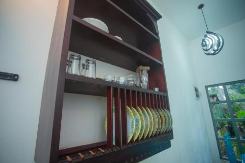 a shelf in a room with books and glasses at Percy Residence in Unawatuna