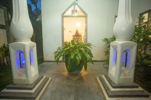 two white vases sitting next to a plant and a mirror at Percy Residence in Unawatuna