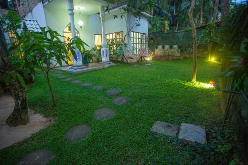 a backyard with a yard with rocks in the grass at Percy Residence in Unawatuna