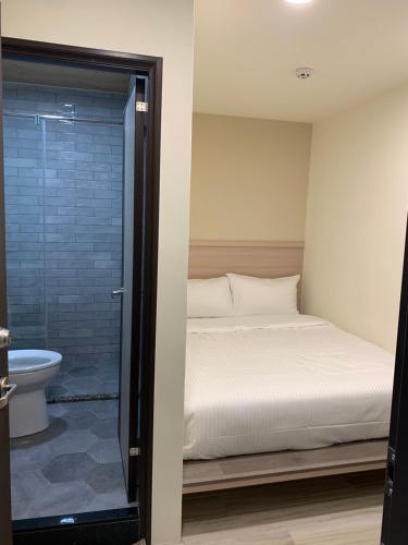 um quarto com uma cama e uma cabina de duche em vidro em 晶晶輕旅民宿 em Ruifang
