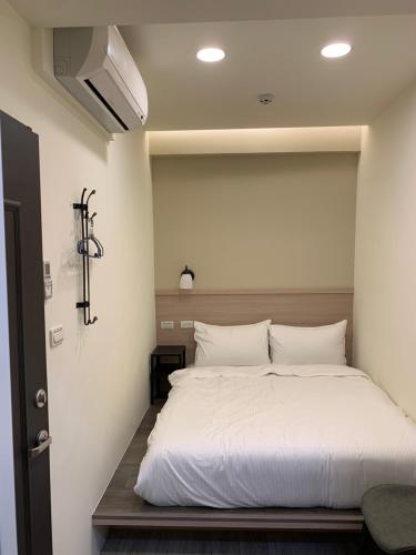 een slaapkamer met een groot bed met witte lakens bij 晶晶輕旅民宿 in Ruifang