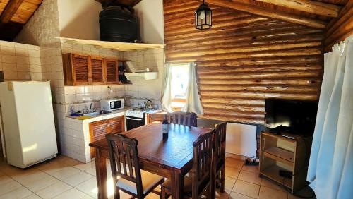 a kitchen with a table with chairs and a refrigerator at Cabañas Premium Mirador Azul in Potrerillos