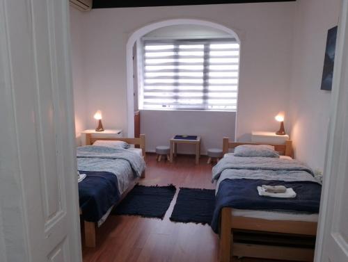 2 Einzelbetten in einem Zimmer mit Fenster in der Unterkunft Mili Host in Belgrad