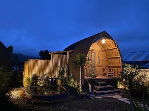 Tegal Bamboo cottages & private hot spring في Baturaja: منزل حرباء صغير مع نافورة في الفناء