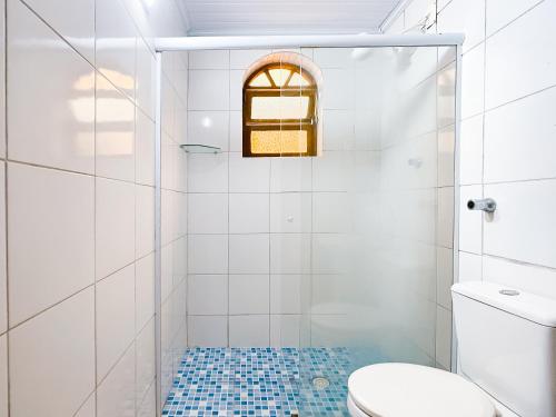 a white bathroom with a shower and a toilet at Geko Pousada Paraty in Paraty