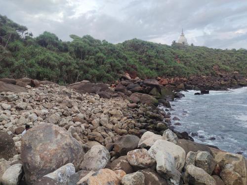 a group of rocks on the shore of the water at Moon Light Rest in Galle